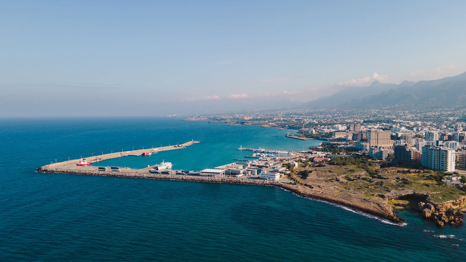 Aerial view of a coastal city with a vibrant harbor and a clear blue sky.